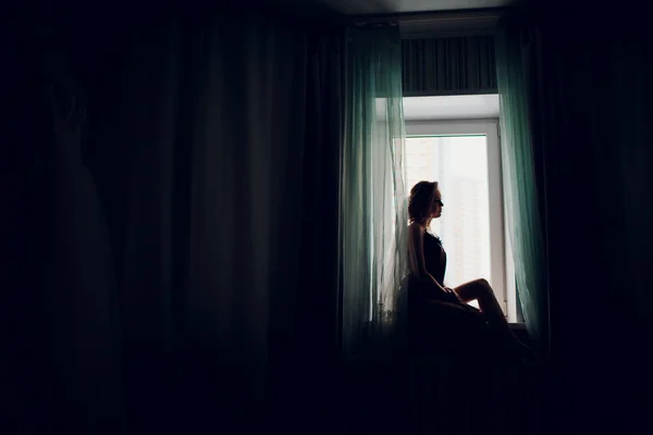 Lány esküvői fátyol közelében egy ablak, egy sötét szobában — Stock Fotó