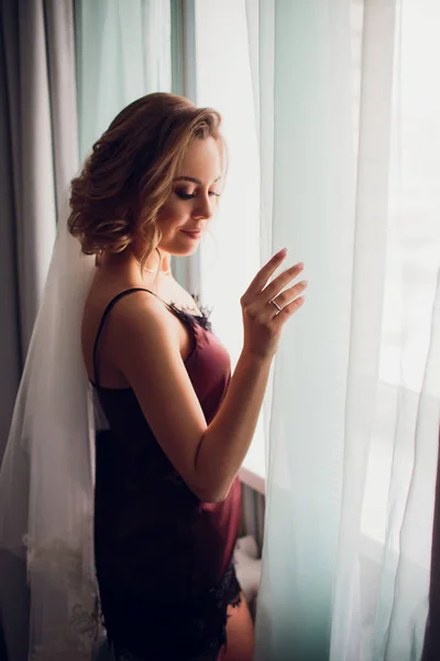 Дівчина в весільній вуалі біля вікна в темній кімнаті — стокове фото
