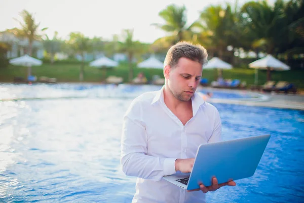 Young freelancer working on vacation next to the swimming pool