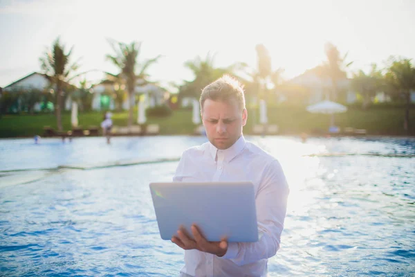 Young freelancer working on vacation next to the swimming pool