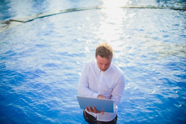 Young freelancer working on vacation next to the swimming pool