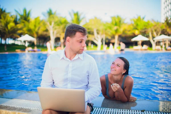 woman distracting from the work of a freelancer man on a pool background