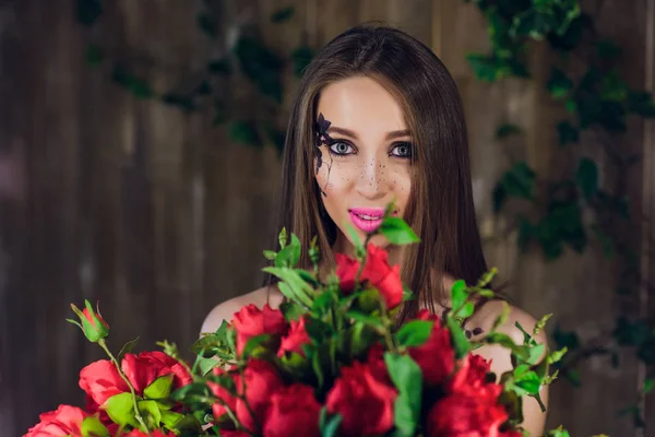 Jovem linda menina bonita de pé e segurando caixa com rosas vermelhas. Vogue moda estilo estúdio retrato menina em preto elegante vestido de pé — Fotografia de Stock