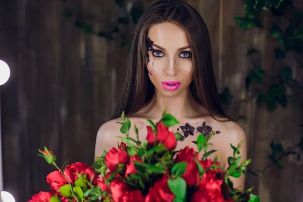 Krásná mladá hezká dívka stojí a drží box s červenými růžemi. Vogue módní styl studio portrét dívka v černé elegantní šaty stojící — Stock fotografie