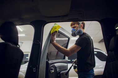 Yakışıklı adam sıcak buharla araba temizliyor.