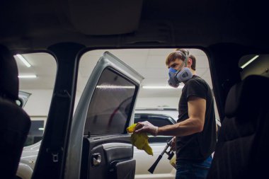 Yakışıklı adam sıcak buharla araba temizliyor.