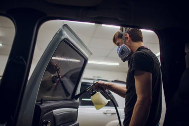 Yakışıklı adam sıcak buharla araba temizliyor.