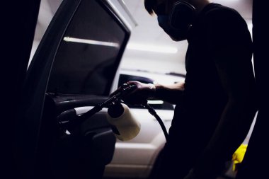 Yakışıklı adam sıcak buharla araba temizliyor.