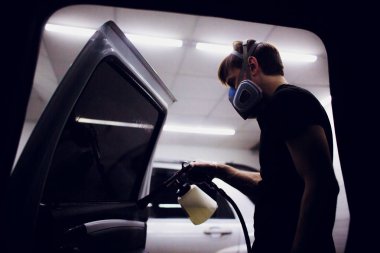 Yakışıklı adam sıcak buharla araba temizliyor.