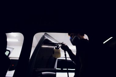 Yakışıklı adam sıcak buharla araba temizliyor.