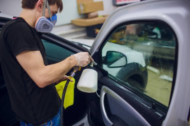 Yakışıklı adam sıcak buharla araba temizliyor.