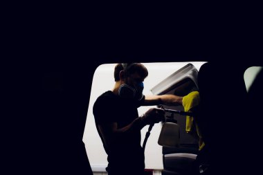 Yakışıklı adam sıcak buharla araba temizliyor.