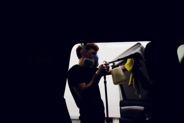 Yakışıklı adam sıcak buharla araba temizliyor.