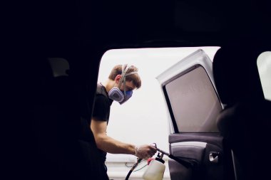 Yakışıklı adam sıcak buharla araba temizliyor.