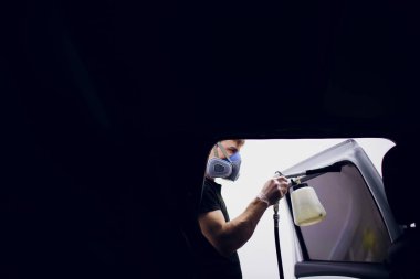 Yakışıklı adam sıcak buharla araba temizliyor.