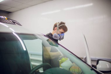 Yakışıklı adam sıcak buharla araba temizliyor.