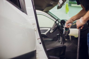 Yakışıklı adam sıcak buharla araba temizliyor.