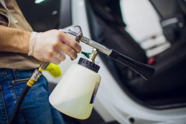 Yakışıklı adam sıcak buharla araba temizliyor.