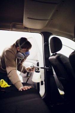 Yakışıklı adam sıcak buharla araba temizliyor.