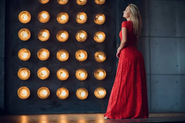 Holidays and fashion concept - beautiful sexy woman in red dress over lights background — Stock Photo, Image