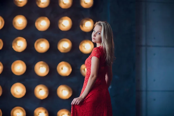 Holidays and fashion concept - beautiful sexy woman in red dress over lights background — Stock Photo, Image