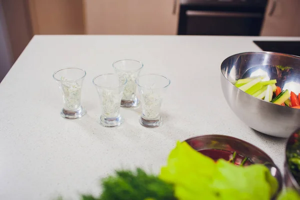 Chief cook preparing fresh salad with sauce in glass