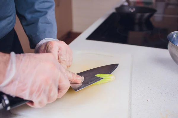 Ama de casa corte apio cocinero en la cocina. Manos Cortando apio con cuchillo sobre tabla de madera. Cocina en concepto de cocina . — Foto de Stock