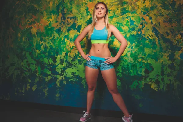 Horizontale Aufnahme der schlanken, sportlichen Frau hat einen schönen gesunden, muskulösen Körper, bekleidet mit lässigem Oberteil und kurzen Hosen. Athletikerin legt nach Training Pause ein. — Stockfoto
