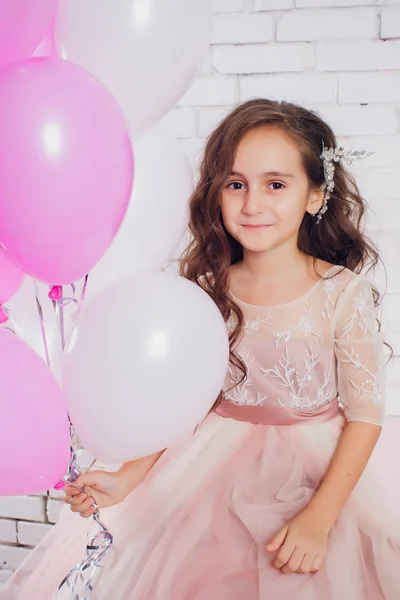 Beautiful little girl sitting near to a Christmas tree. Charming daughter in pink dress. New year gift. — Stock Photo, Image