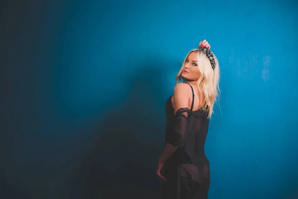 Blondine auf blauem Hintergrund mit schwarzem Baud und Hut. — Stockfoto