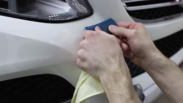 Inquadratura ravvicinata delle mani dell'uomo che sblocca il film con un'auto costosa con cappuccio bianco. Questo film protegge il veicolo dalla pittura ruvida . — Video Stock