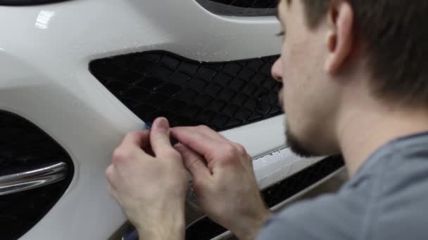 Close up shot of the hands of man who unstick the film with white cowl expensive car. This film protects the vehicle from the rough painting. — Stock Video