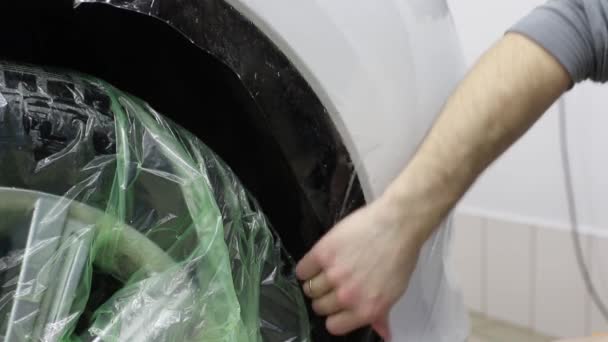 Gros plan des mains de l'homme qui décollent le film avec une voiture de luxe à capot blanc. Ce film protège le véhicule de la peinture rugueuse . — Video