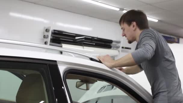 Primer plano de las manos del hombre que despegan la película con la capucha blanca coche caro. Esta película protege el vehículo de la pintura en bruto . — Vídeos de Stock