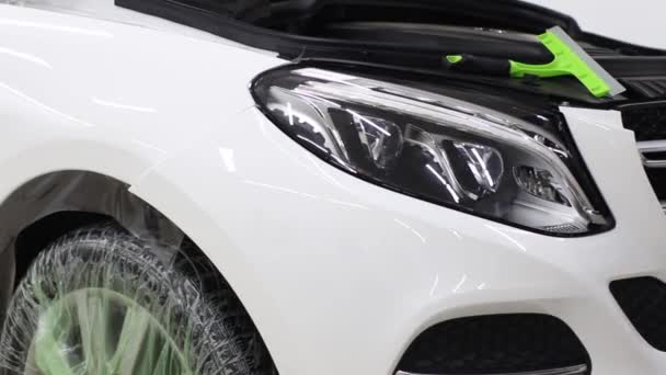 Close up shot of the hands of man who unstick the film with white cowl expensive car. This film protects the vehicle from the rough painting. — Stock Video