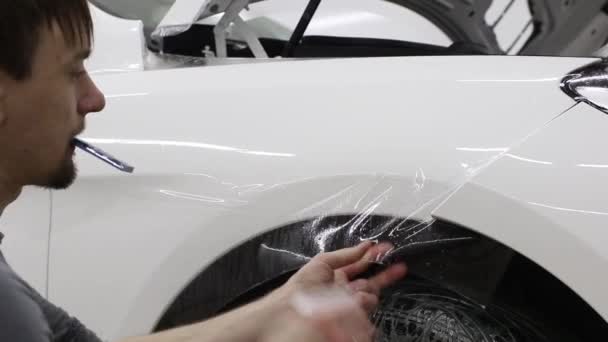Close up shot of the hands of man who unstick the film with white cowl expensive car. This film protects the vehicle from the rough painting. — Stock Video