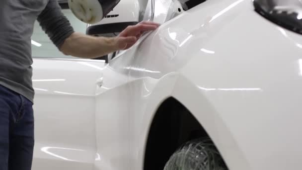 Κοντινό πλάνο της τα χέρια του ανθρώπου που ξεκολλήσει η ταινία με λευκό φέρινγκ ακριβό αυτοκίνητο. Αυτή η ταινία προστατεύει το όχημα από το τραχύ ζωγραφική. — Αρχείο Βίντεο