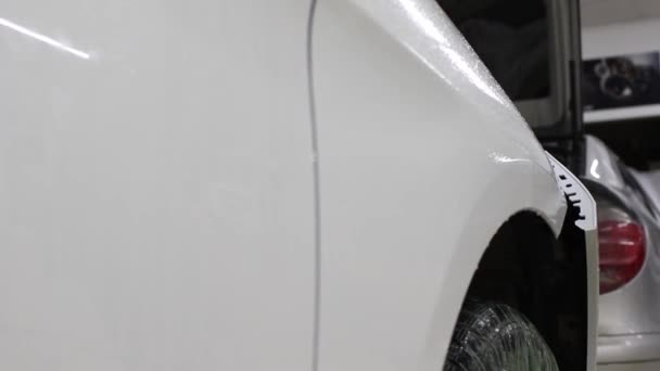 Close up tiro das mãos do homem que descolar o filme com capuz branco carro caro. Este filme protege o veículo da pintura áspera . — Vídeo de Stock