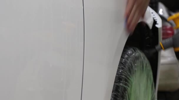 Close up shot of the hands of man who unstick the film with white cowl expensive car. This film protects the vehicle from the rough painting. — Stock Video