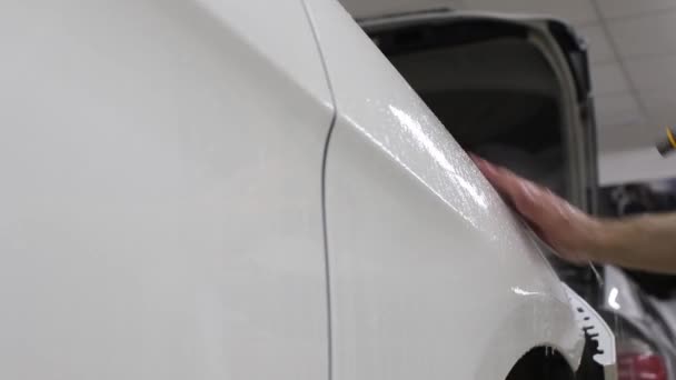 白いカウル高価な車が付いているフィルムをはがれる人男の手のショットを閉じる。この映画は、ラフ絵から車両を保護します。. — ストック動画
