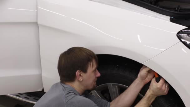 Primer plano de las manos del hombre que despegan la película con la capucha blanca coche caro. Esta película protege el vehículo de la pintura en bruto . — Vídeos de Stock