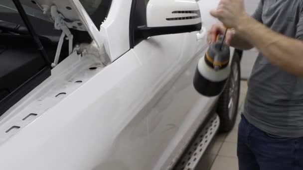 Primer plano de las manos del hombre que despegan la película con la capucha blanca coche caro. Esta película protege el vehículo de la pintura en bruto . — Vídeo de stock