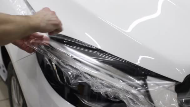 Close up tiro das mãos do homem que descolar o filme com capuz branco carro caro. Este filme protege o veículo da pintura áspera . — Vídeo de Stock