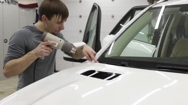 Primer plano de las manos del hombre que despegan la película con la capucha blanca coche caro. Esta película protege el vehículo de la pintura en bruto . — Vídeos de Stock