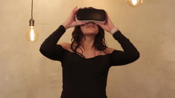 Las mujeres modernas usan gafas de realidad paralela y ven videos o películas con interés, se divierten y comen palomitas de maíz mientras están sentadas en un dormitorio luminoso por la noche. Mujer joven de aspecto europeo con medio — Vídeos de Stock