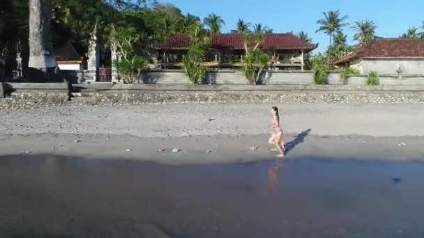Sziluettjét fiatal lány futás tenger beach egy csodálatos naplemente alatt. — Stock videók