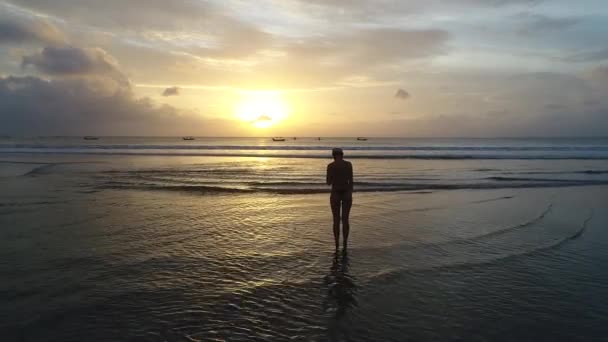 Ung kvinne som går alene på stranden i solnedgang – stockvideo