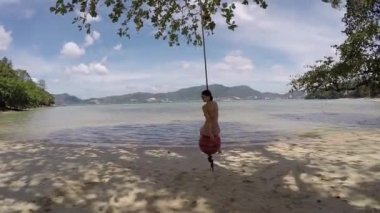 Güzel mutlu tabaklanmış inanılmaz lüks genç kız rides ip üzerinde bikini Plajı'nda bir geniş şapka, tatil salıncak bir tropik ada, sağlıklı cilt ve saç, mükemmel bir vücut, yaşam tarzı üzerinde