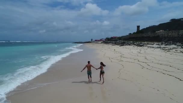 Mujer joven y hombre pareja caminando en la playa en la puesta del sol — Vídeos de Stock