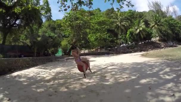 Linda alegre bronzeada incrível luxo jovem passeios de corda balançar na praia de biquíni em um chapéu largo, férias em uma ilha tropical, pele saudável e cabelo, corpo perfeito, estilo de vida — Vídeo de Stock